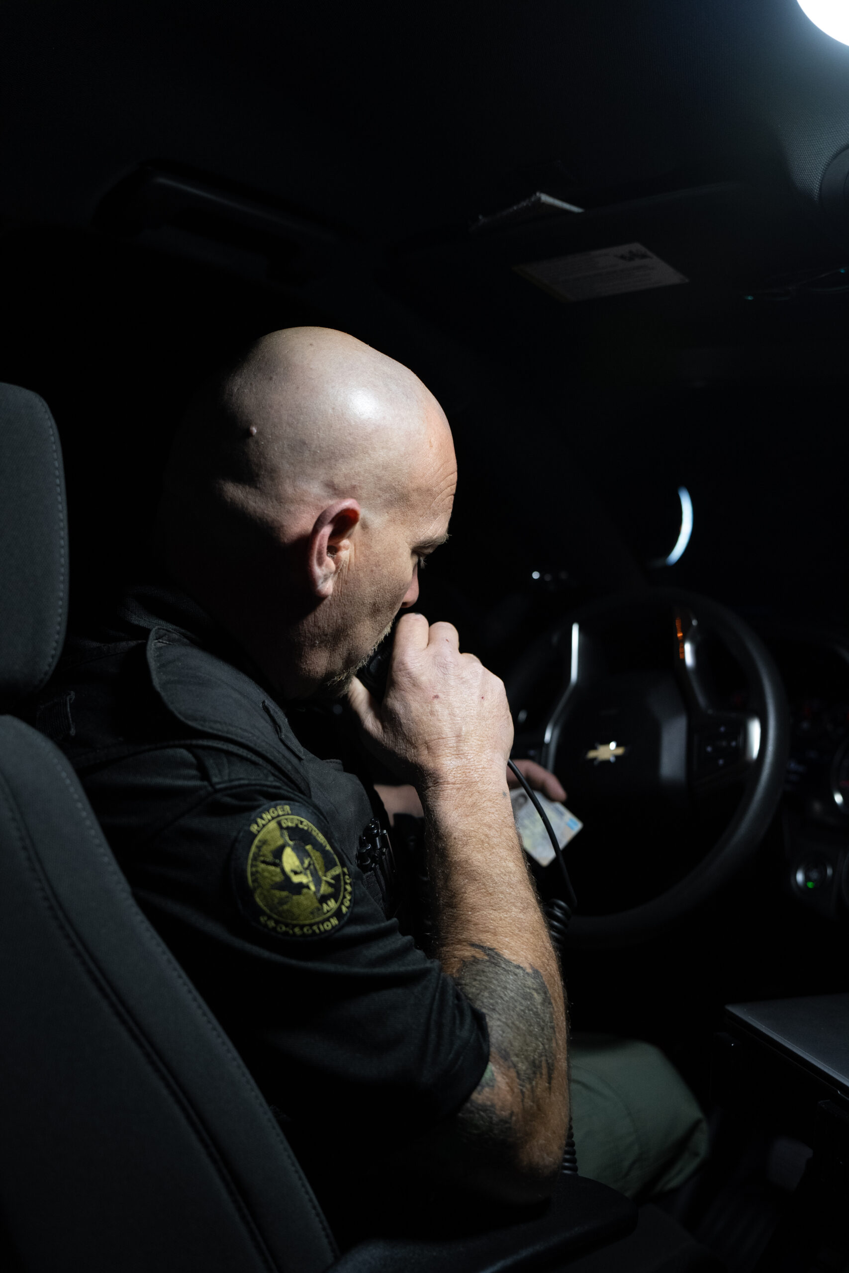 Ranger Protection Agency security officer communicating by radio while inside a patrol vehicle